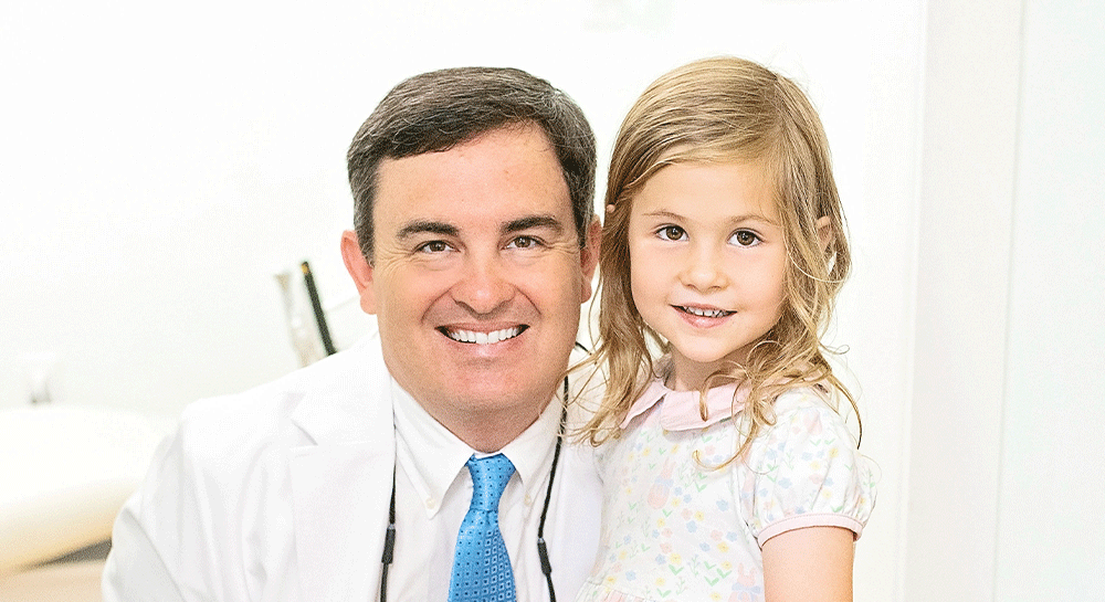 Dr. Green wearing a white coat and blue tie, with a stethoscope around the neck, indicating a professional role, likely in the medical or dental field. The second person is a child in a light-colored floral dress.