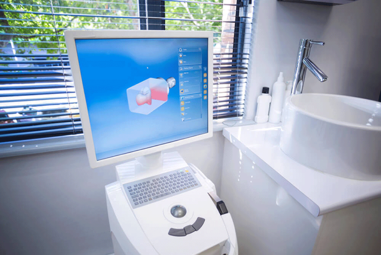 A dental CAD/CAM (computer-aided design and computer-aided manufacturing) system in a dental office. The setup includes a computer with a monitor displaying a 3D model of a dental restoration and a milling machine used to fabricate the dental restoration based on the digital design.
