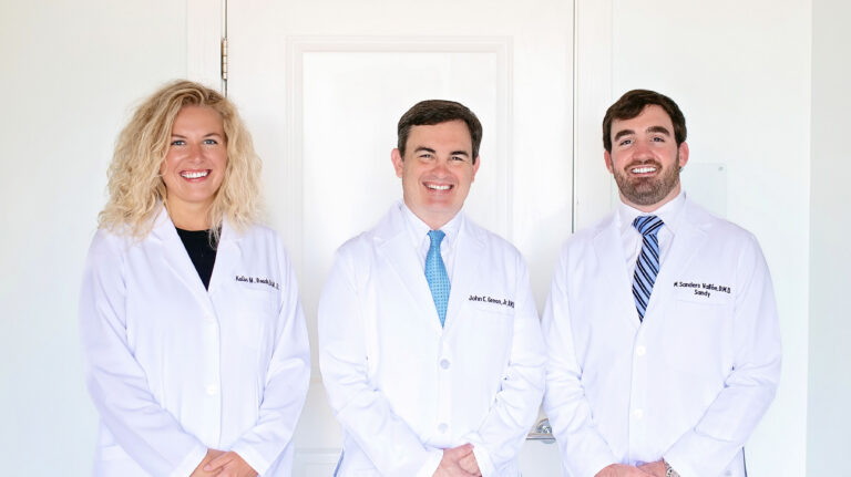 Dentists at Point Clear Dental Associates standing side by side in front of a clinic door